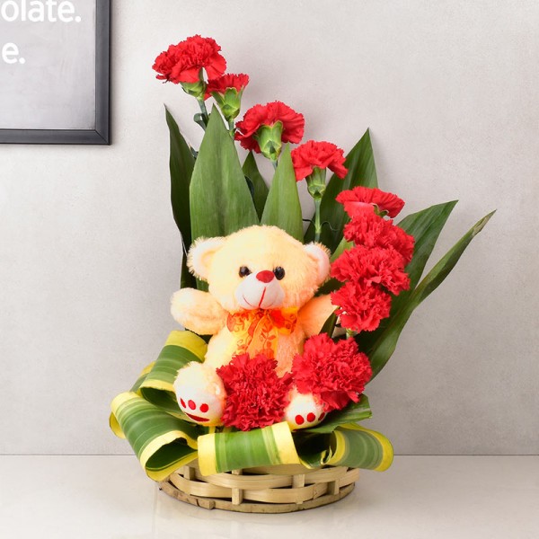 12 Red Carnations arranged in a basket with Teddy Bear (6 inches)