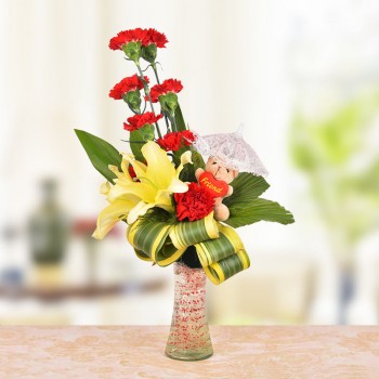 Floral Arrangement of 8 Red Carnations, 2 Yellow Asiatic Lilies and a 3 Inches Brown Teddy Bear with dracaena leaves