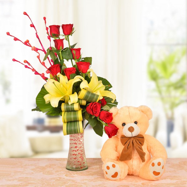 Floral Arrangement of 8 Red Roses, 2 Yellow Asiatic Lilies with dracaena leaves in a Glass Vase with 1 Brown Teddy Bear (12 Inches)