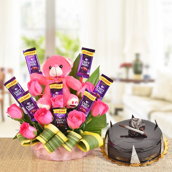 A Basket Arrangement of 8 Pink roses, 8 Cadbury's Dairy Milk of 13 gms each and a pink Teddy bear (6 Inches) with dracaena leaves with Half Kg Chocolate Truffle Cake