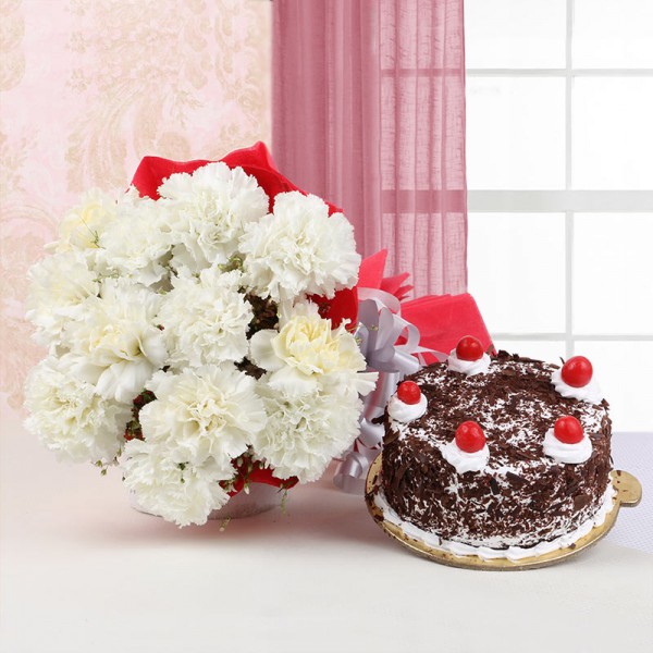 12 White Carnations in Red Paper Packing with Black Forest Cake (Half Kg)