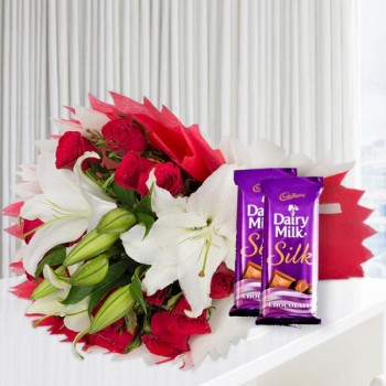 A bunch of Flowers (12 Red Roses, 3 White Asiatic Lily) in Red and White Paper Packing, White Paper Bow with 2 Cadbury's DairyMilk Silk (60gms each)